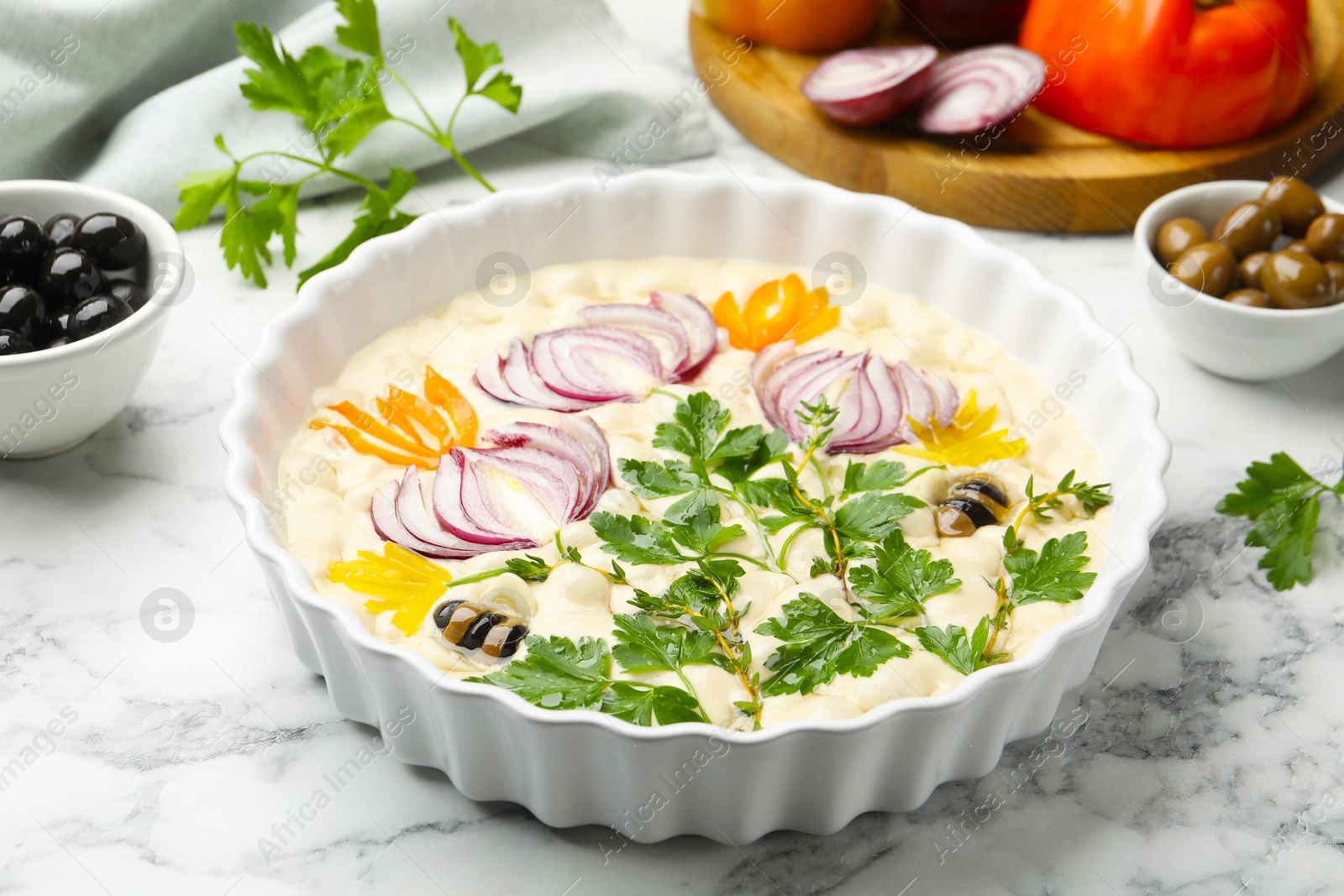 Raw focaccia with vegetables and olives on white marble table, closeup Photo of Raw focaccia with vegetables and olives on white marble table, closeup