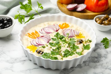 Photo of Raw focaccia with vegetables and olives on white marble table, closeup