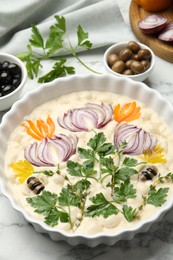 Photo of Raw focaccia with vegetables and olives on white marble table, closeup