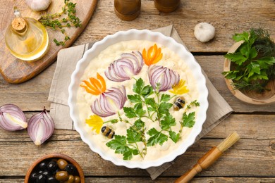 Photo of Raw focaccia with vegetables, olives, spices and brush on wooden table, flat lay