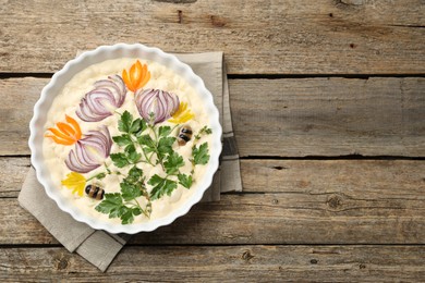 Photo of Raw focaccia with vegetables and olives in baking dish on wooden table, top view. Space for text
