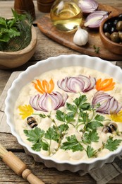 Photo of Raw focaccia with vegetables, olives, spices and brush on wooden table, closeup