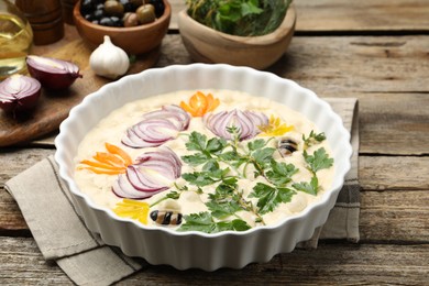 Photo of Raw focaccia with vegetables, olives and spices on wooden table, closeup