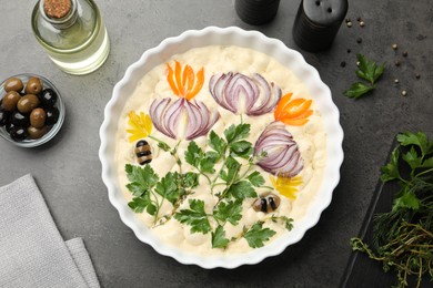 Photo of Raw focaccia with vegetables, olives and spices on grey table, flat lay