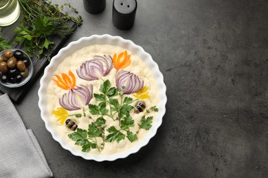Photo of Raw focaccia with vegetables, olives and spices on grey table, flat lay. Space for text