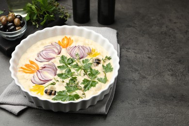 Photo of Raw focaccia with vegetables, olives and spices on grey table, closeup. Space for text