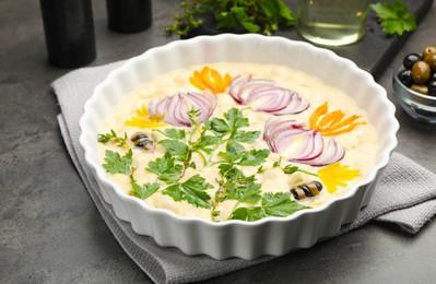 Photo of Raw focaccia with vegetables, olives and spices on grey table, closeup