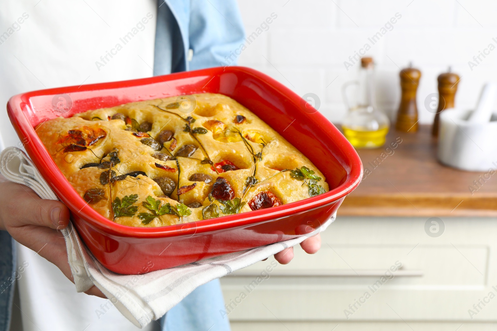 Woman holding delicious focaccia with vegetables and olives in kitchen, closeup Photo of Woman holding delicious focaccia with vegetables and olives in kitchen, closeup