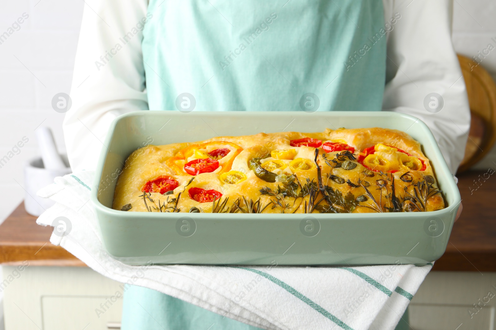 Woman holding delicious focaccia with vegetables and olives in kitchen, closeup Photo of Woman holding delicious focaccia with vegetables and olives in kitchen, closeup