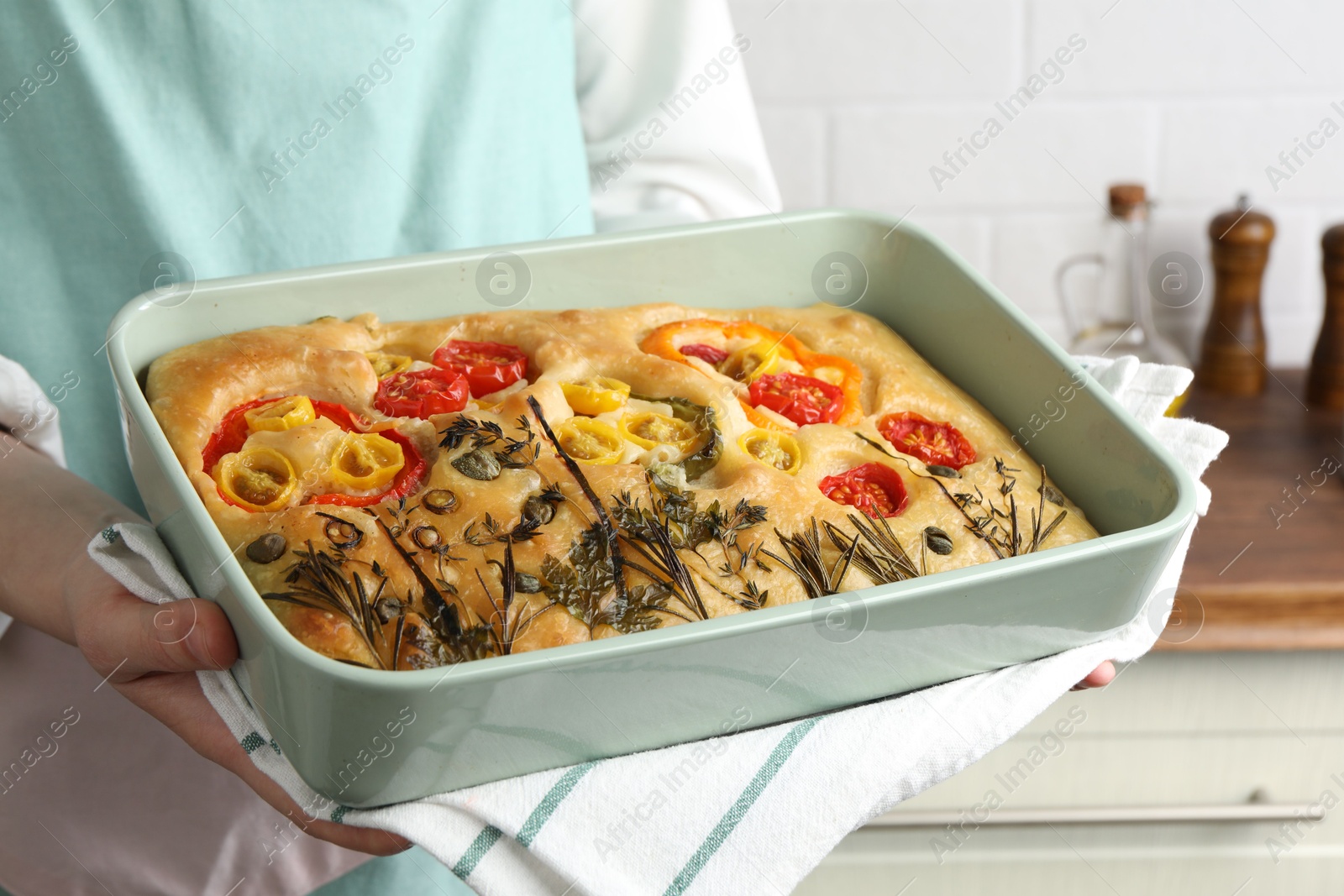 Woman holding delicious focaccia with vegetables and olives in kitchen, closeup Photo of Woman holding delicious focaccia with vegetables and olives in kitchen, closeup