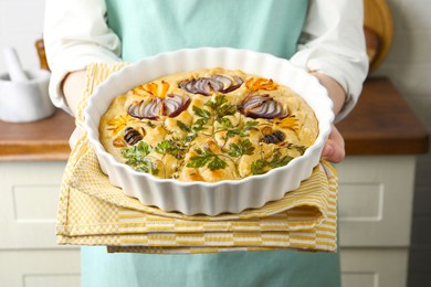 Photo of Woman holding delicious focaccia with vegetables and olives in kitchen, closeup