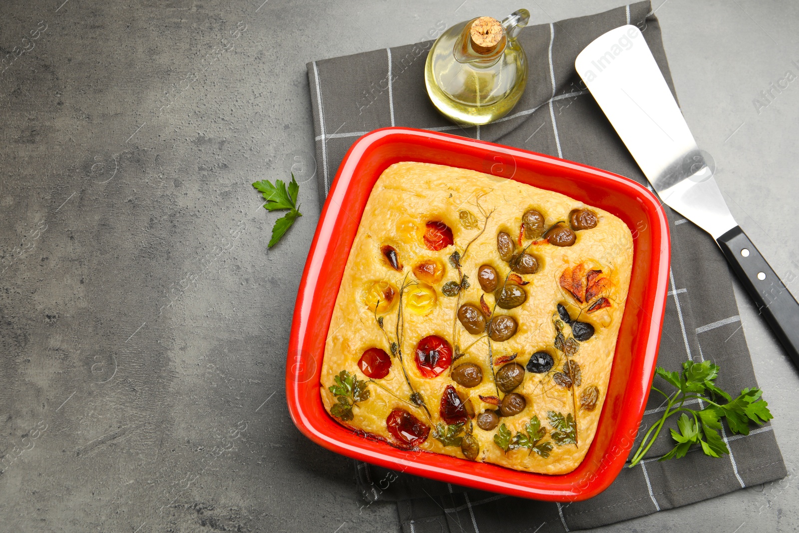 Delicious focaccia with vegetables, olives, spices and server on grey table, flat lay. Space for text Photo of Delicious focaccia with vegetables, olives, spices and server on grey table, flat lay. Space for text