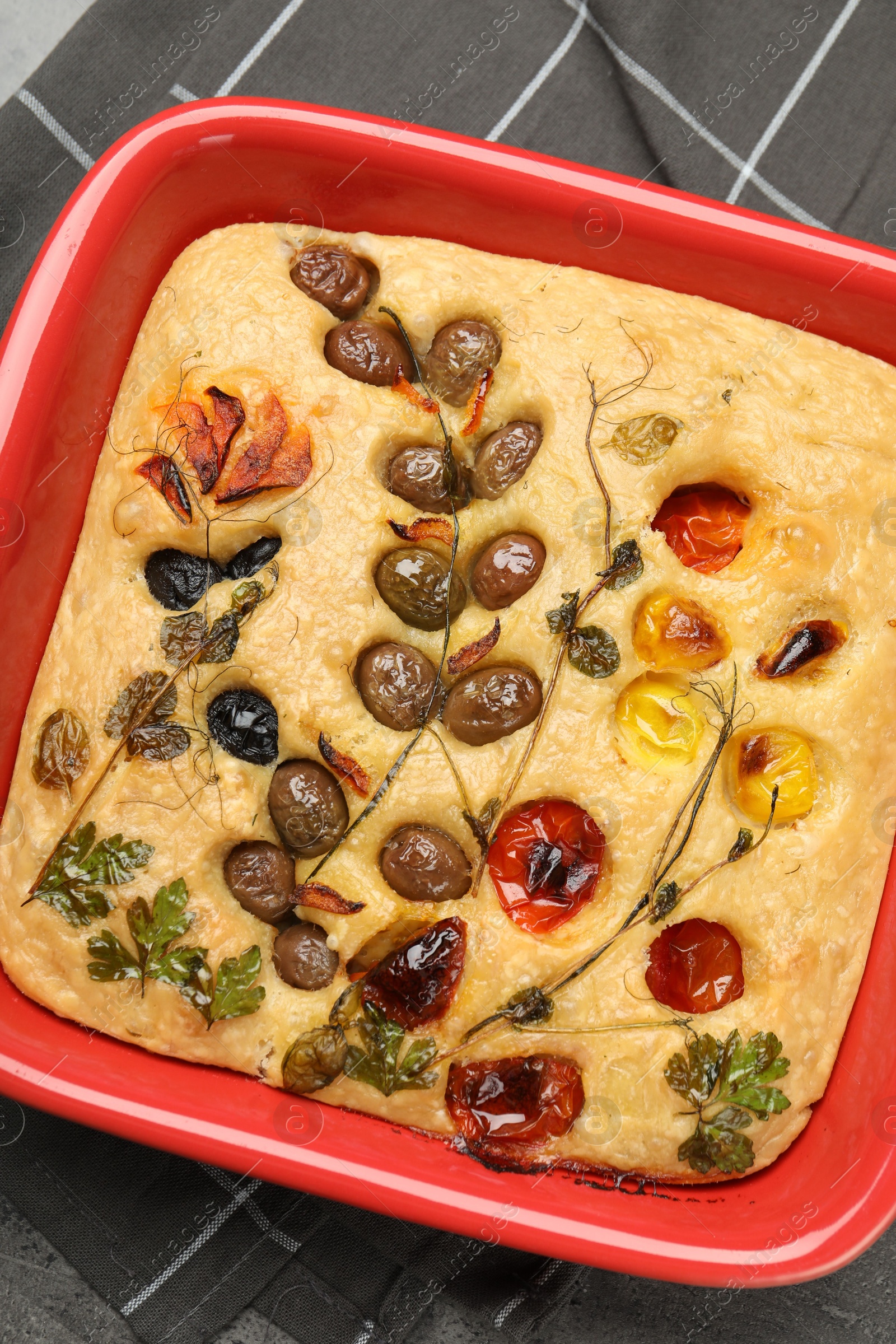 Delicious focaccia with vegetables and olives in baking dish on table, top view Photo of Delicious focaccia with vegetables and olives in baking dish on table, top view
