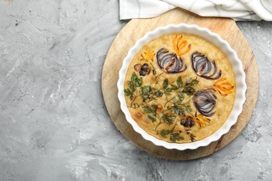 Photo of Delicious focaccia with flowers made of vegetables on grey textured table, top view. Space for text