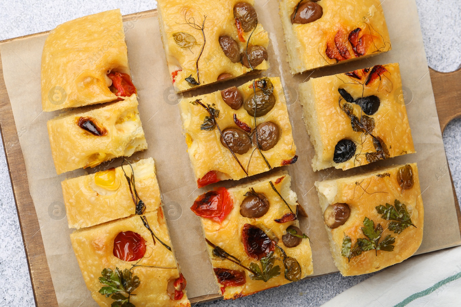 Cut delicious focaccia with flowers made of vegetables on light grey table, top view Photo of Cut delicious focaccia with flowers made of vegetables on light grey table, top view
