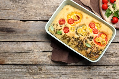 Photo of Delicious focaccia with flowers made of vegetables on wooden table, top view. Space for text