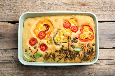 Photo of Delicious focaccia with flowers made of vegetables on wooden table, top view