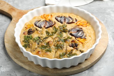 Photo of Delicious focaccia with flowers made of vegetables on grey textured table, closeup