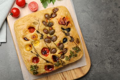 Photo of Delicious focaccia with flowers made of vegetables on grey table, top view