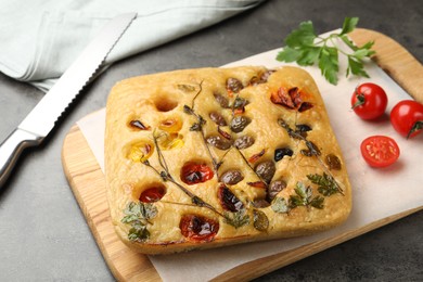 Photo of Delicious focaccia with flowers made of vegetables on grey table