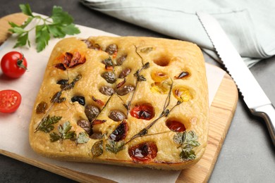 Photo of Delicious focaccia with flowers made of vegetables on grey table, closeup