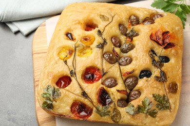 Photo of Delicious focaccia with flowers made of vegetables on light grey table, closeup