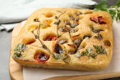 Photo of Delicious focaccia with flowers made of vegetables on light grey table, closeup