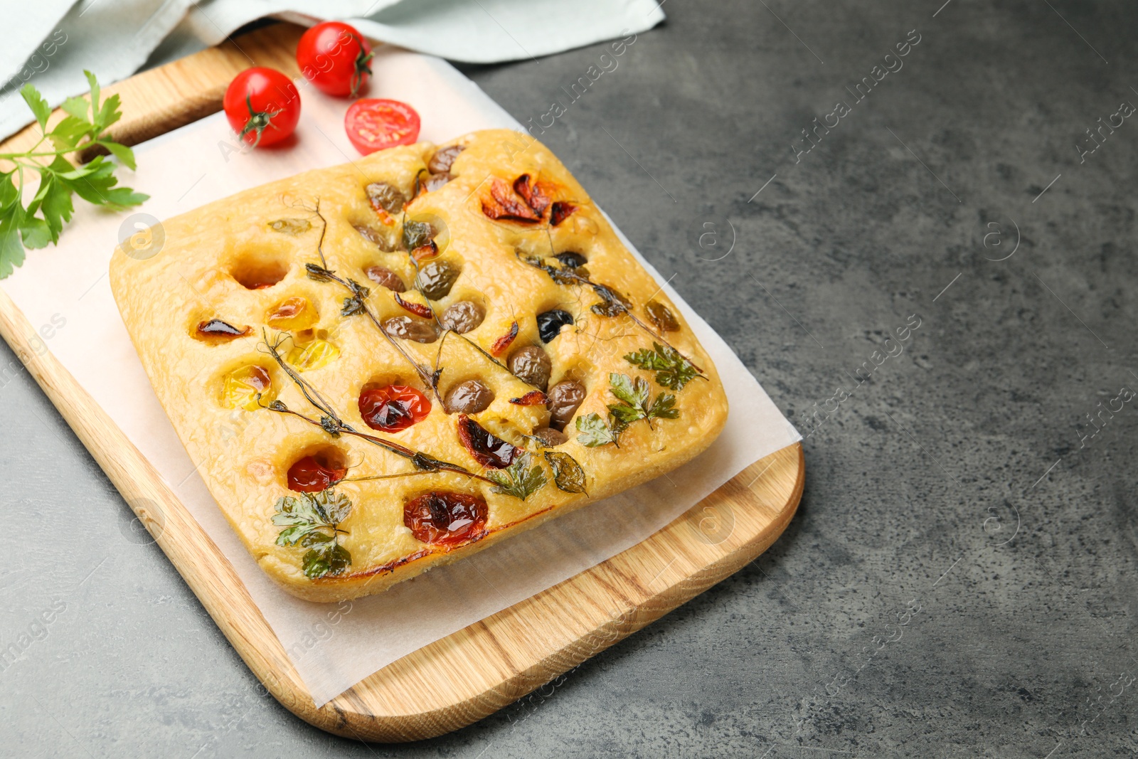 Delicious focaccia with flowers made of vegetables on grey table. Space for text Photo of Delicious focaccia with flowers made of vegetables on grey table. Space for text