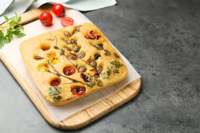 Photo of Delicious focaccia with flowers made of vegetables on grey table. Space for text