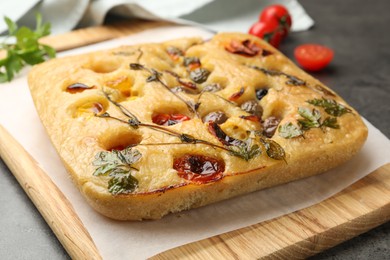 Photo of Delicious focaccia with flowers made of vegetables on grey table, closeup