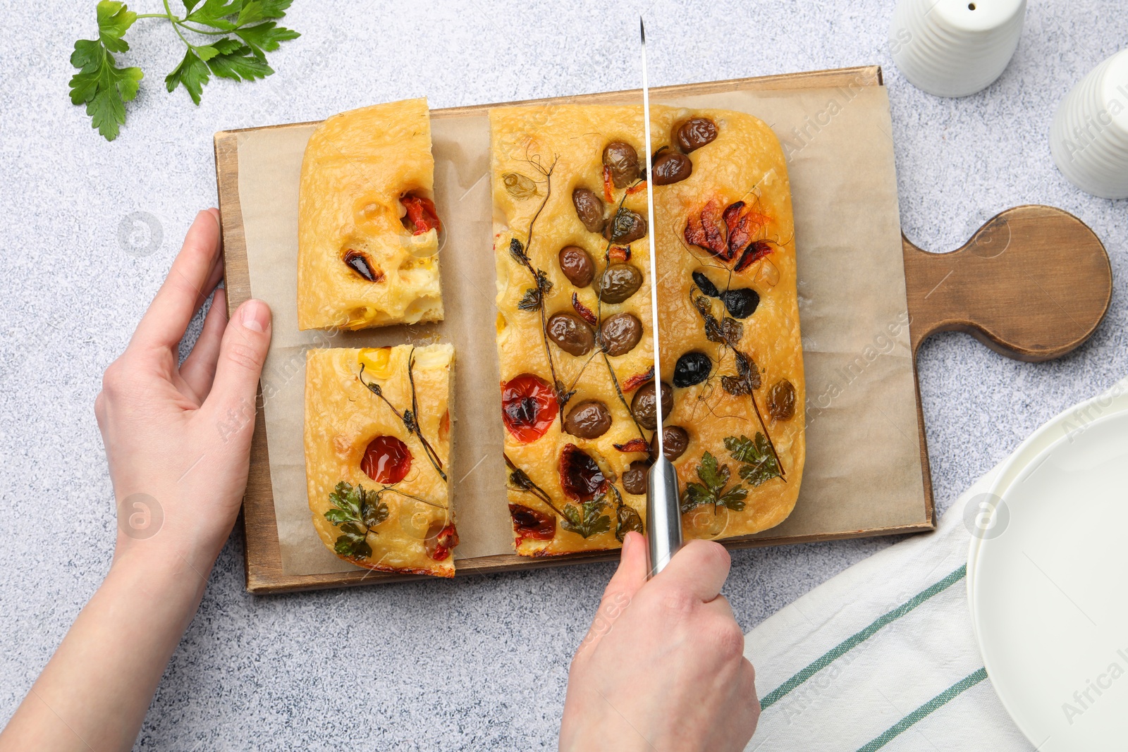 Woman cutting delicious focaccia at light grey table, top view Photo of Woman cutting delicious focaccia at light grey table, top view