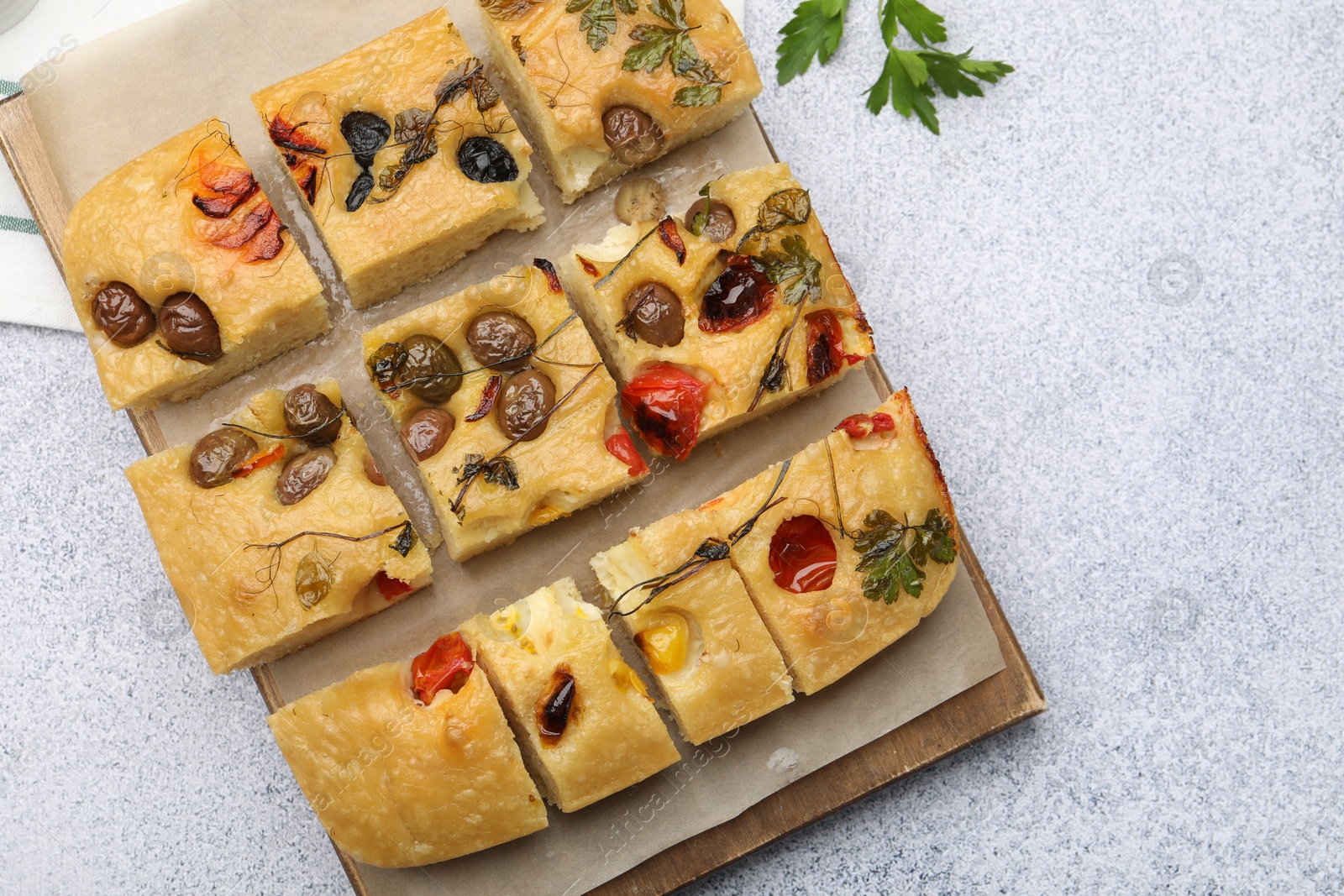 Cut delicious focaccia with flowers made of vegetables on light grey table, top view Photo of Cut delicious focaccia with flowers made of vegetables on light grey table, top view