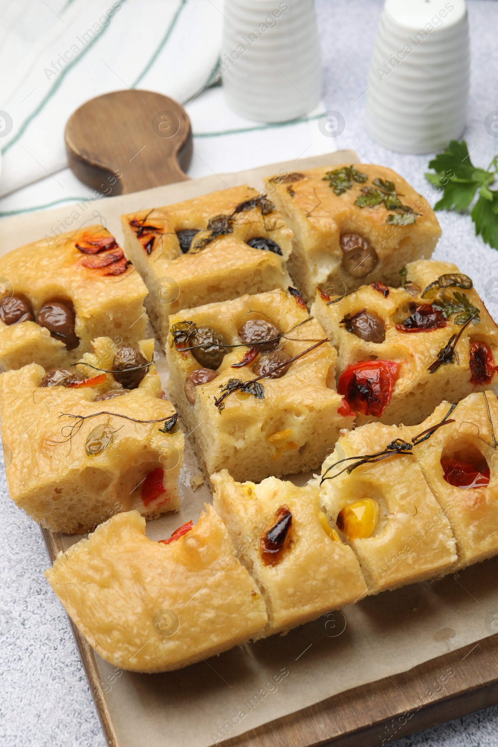 Cut delicious focaccia with flowers made of vegetables on light grey table, closeup Photo of Cut delicious focaccia with flowers made of vegetables on light grey table, closeup