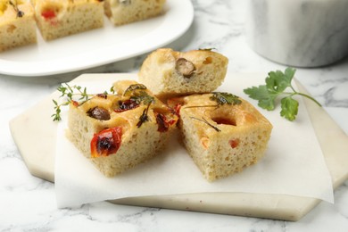 Photo of Pieces of delicious focaccia on white marble table, closeup