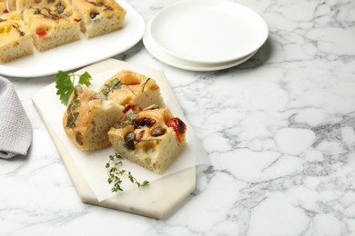 Photo of Pieces of delicious focaccia on white marble table. Space for text