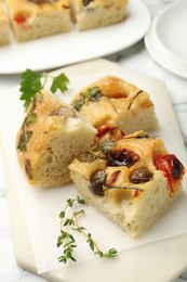 Photo of Pieces of delicious focaccia on white table, closeup