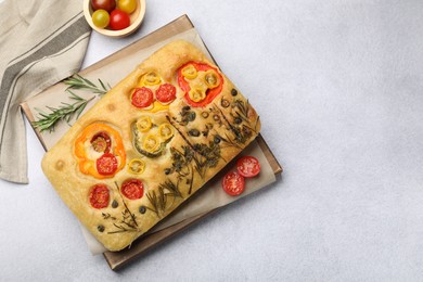 Photo of Delicious focaccia with flowers made of vegetables on light grey table, top view. Space for text