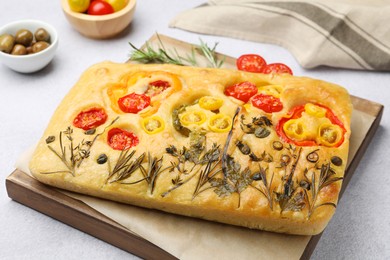 Photo of Delicious focaccia with flowers made of vegetables on light grey table, closeup