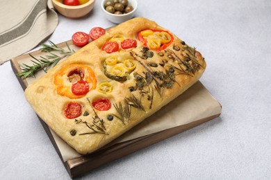 Photo of Delicious focaccia with flowers made of vegetables on light grey table