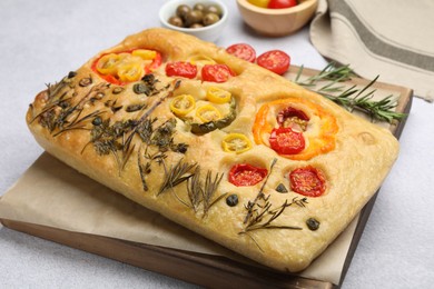Photo of Delicious focaccia with flowers made of vegetables on light grey table, closeup