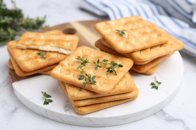 Photo of Tasty salty crackers with thyme on white marble table, closeup