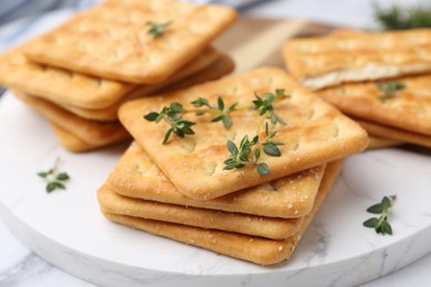 Photo of Tasty salty crackers with thyme on white table, closeup