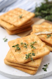 Photo of Tasty salty crackers with thyme on white table, closeup
