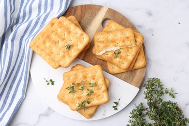Photo of Tasty salty crackers with thyme on white marble table, top view