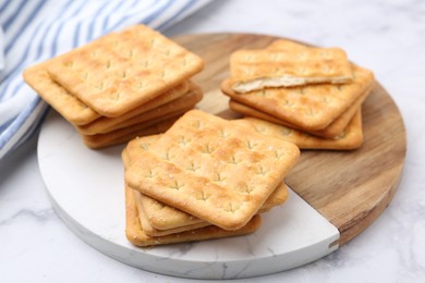 Photo of Tasty salty crackers on white marble table, closeup