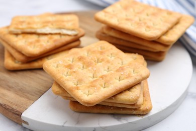 Photo of Tasty salty crackers on white table, closeup