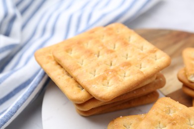 Photo of Tasty salty crackers on white table, closeup