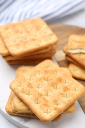Photo of Tasty salty crackers on white table, closeup