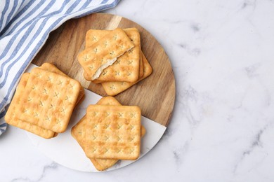 Photo of Tasty salty crackers on white marble table, top view. Space for text
