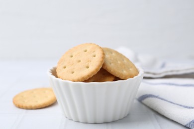 Photo of Tasty salty crackers on white tiled table, closeup